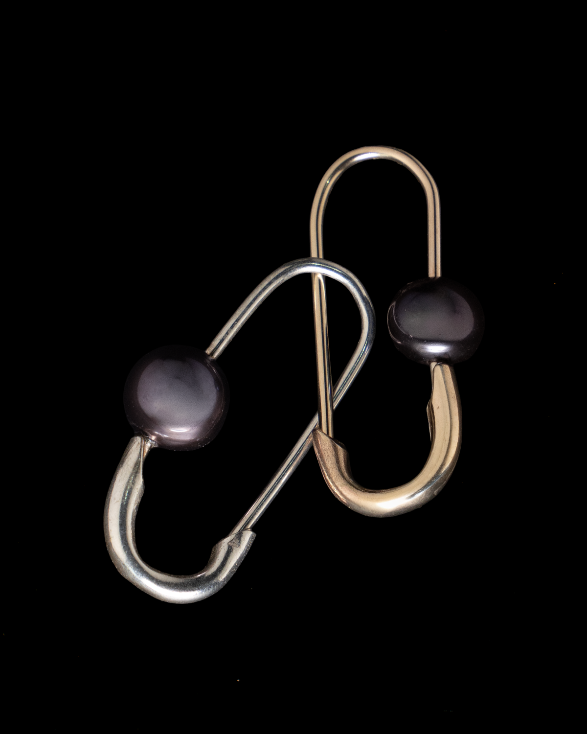 A sterling silver wishbone brooch with draped chains and a pearl, worn on a black knitted coat
