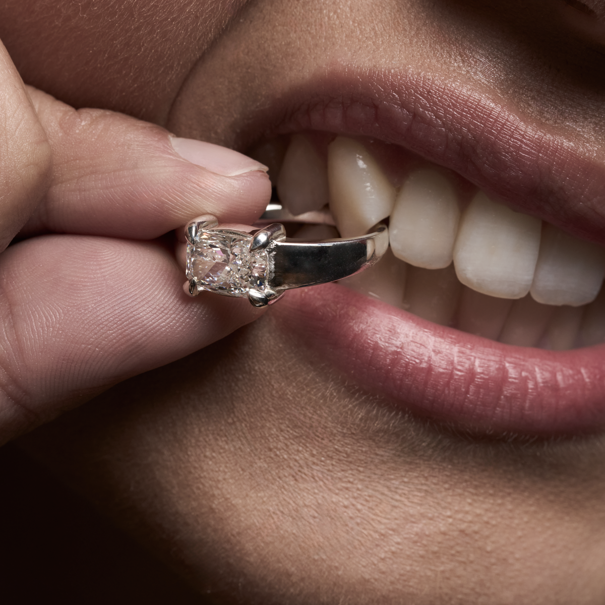 A rose gold serpent ring set with a pear-cut diamond, worn on a hand