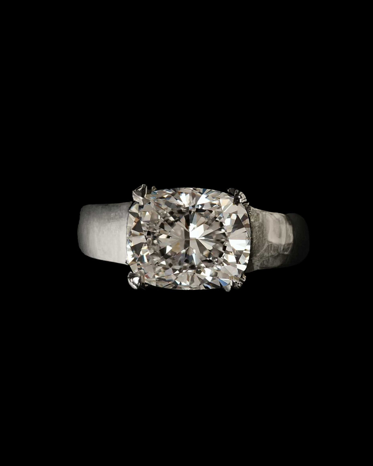 A cushion-cut diamond solitaire in a solid gold band, in an antique black heart-shaped ring box on a gilt tray